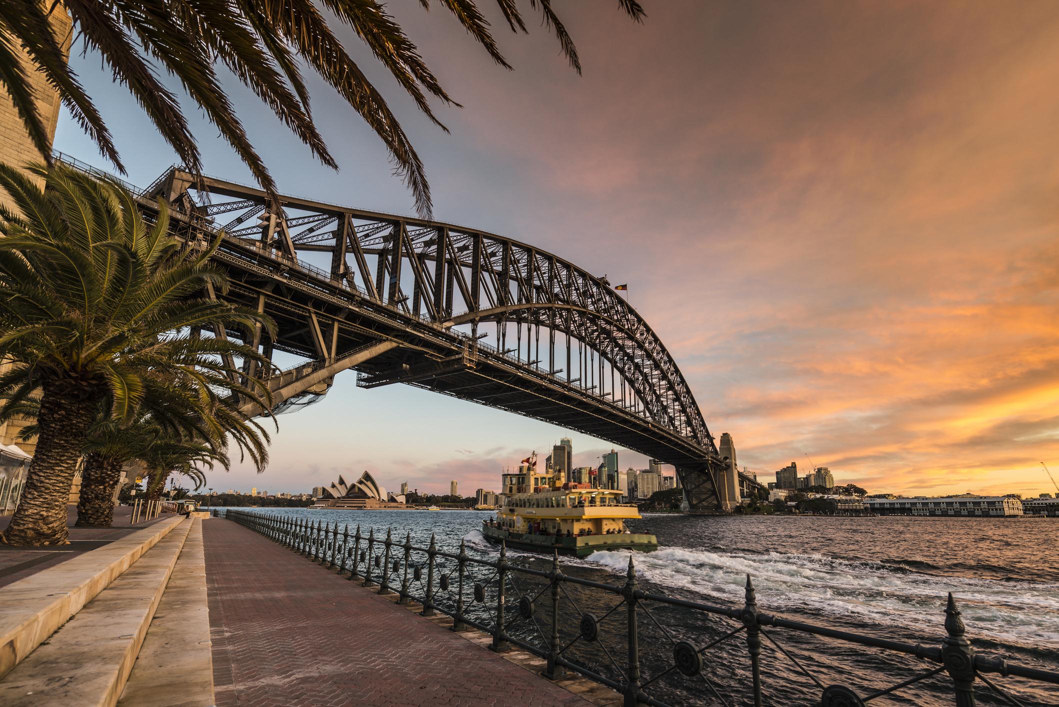 Ferry going under Sydney Harbour Bridge with Sydney Opera House in the background